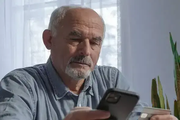 Půjčka pro důchodce - Starší muž používající mobilní telefon