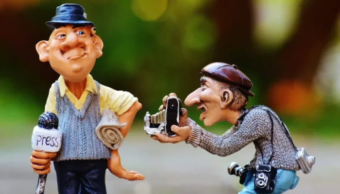 Karikatura novináře s mikrofonem a fotografa pořizujícího snímek